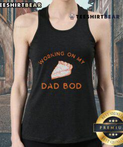 Delicious pie for two on a table, featuring a person in a 'Working on my dad bod' tank top, promoting good eating habits.