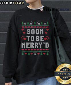 Happy couple wearing matching ugly Christmas sweatshirts, celebrating their engagement in festive holiday spirit.