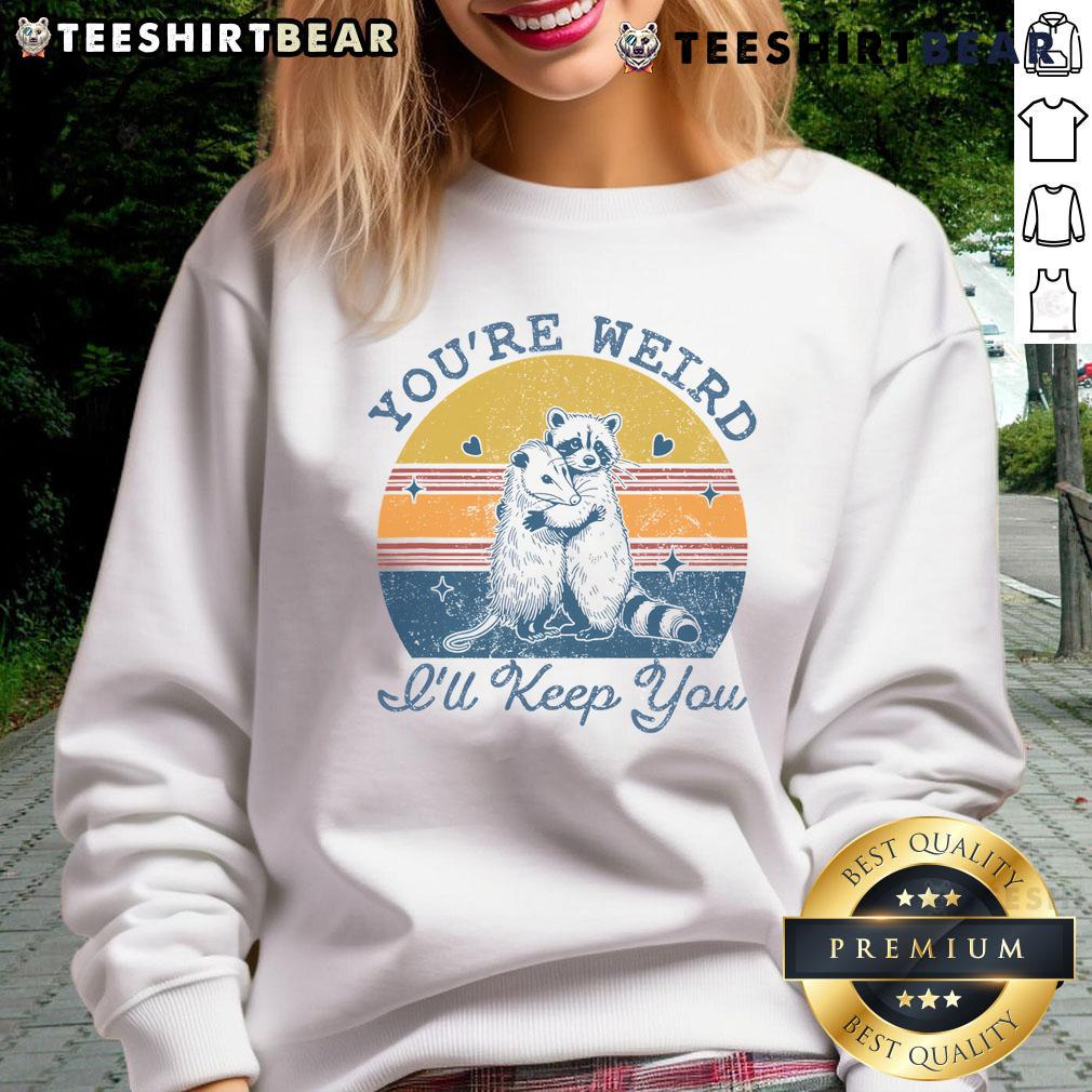 Alt Text: Cute 'Youre Weird, Ill Keep You' sweatshirt against a vibrant sunset backdrop, perfect for cozy casual wear.