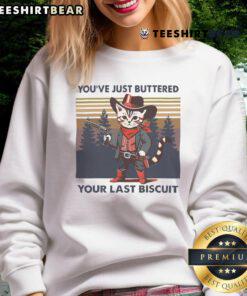 Funny cowboy cat graphic on a sweatshirt with the phrase 'You've Just Buttered Your Last Biscuit' for quirky fashion lovers.