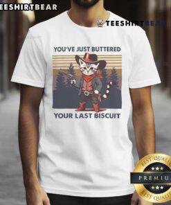 Alt Text: Funny cowboy cat graphic tee featuring You've Just Buttered Your Last Biscuit slogan, perfect for cat lovers.