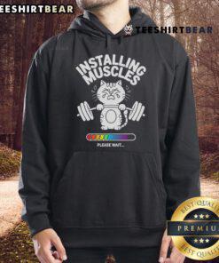 Cat in a fitness hoodie at the gym, humorously showcasing 'Good Installing Muscles' workout motivation.