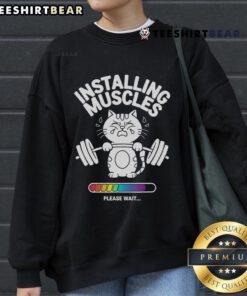 Cat wearing a gym fitness sweatshirt saying 'Good Installing Muscles, Please Wait' during a workout session.