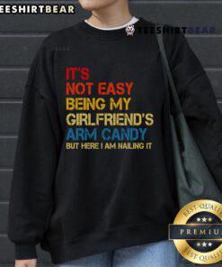 Retro sweatshirt reading 'It's Not Easy Being My Girlfriend's Arm Candy', perfect for casual stylish outfits.