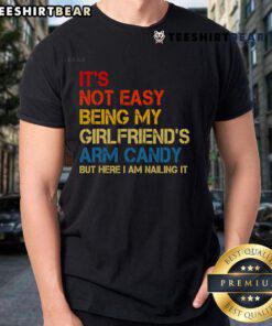 Retro T-shirt featuring 'It's Not Easy Being My Girlfriend's Arm Candy' slogan, perfect for fun casual wear.