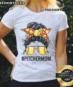 Softball mom with a messy bun wearing a 'Nice Softball Pitcher Mom' tee, cheering on her daughter at the game.