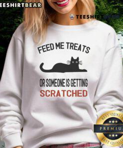 Adorable cat sweatshirt with the phrase 'Feed Me Treats or Someone is Getting Scratched' in playful font.