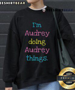 Alt Text: Woman wearing Nice I'm Audrey Doing Audrey Things sweatshirt, showcasing casual style and comfort in a cozy setting.
