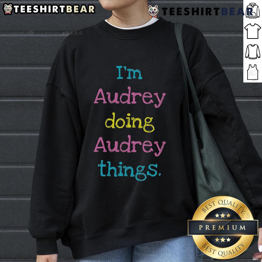 Alt Text: Woman wearing Nice I'm Audrey Doing Audrey Things sweatshirt, showcasing casual style and comfort in a cozy setting.