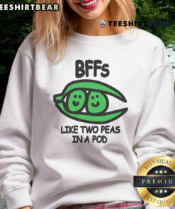 Two friends wearing 'Top BFFs Like Two Peas In A Pod' sweatshirt, showcasing friendship and style in a cozy setting.