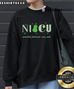 Happy NICU nurse in a retro shamrock sweatshirt celebrating St. Patrick's Day with a cheerful smile.