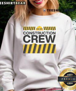 Good construction crew and highway worker party group in matching sweatshirts smiling for a photo at a worksite.