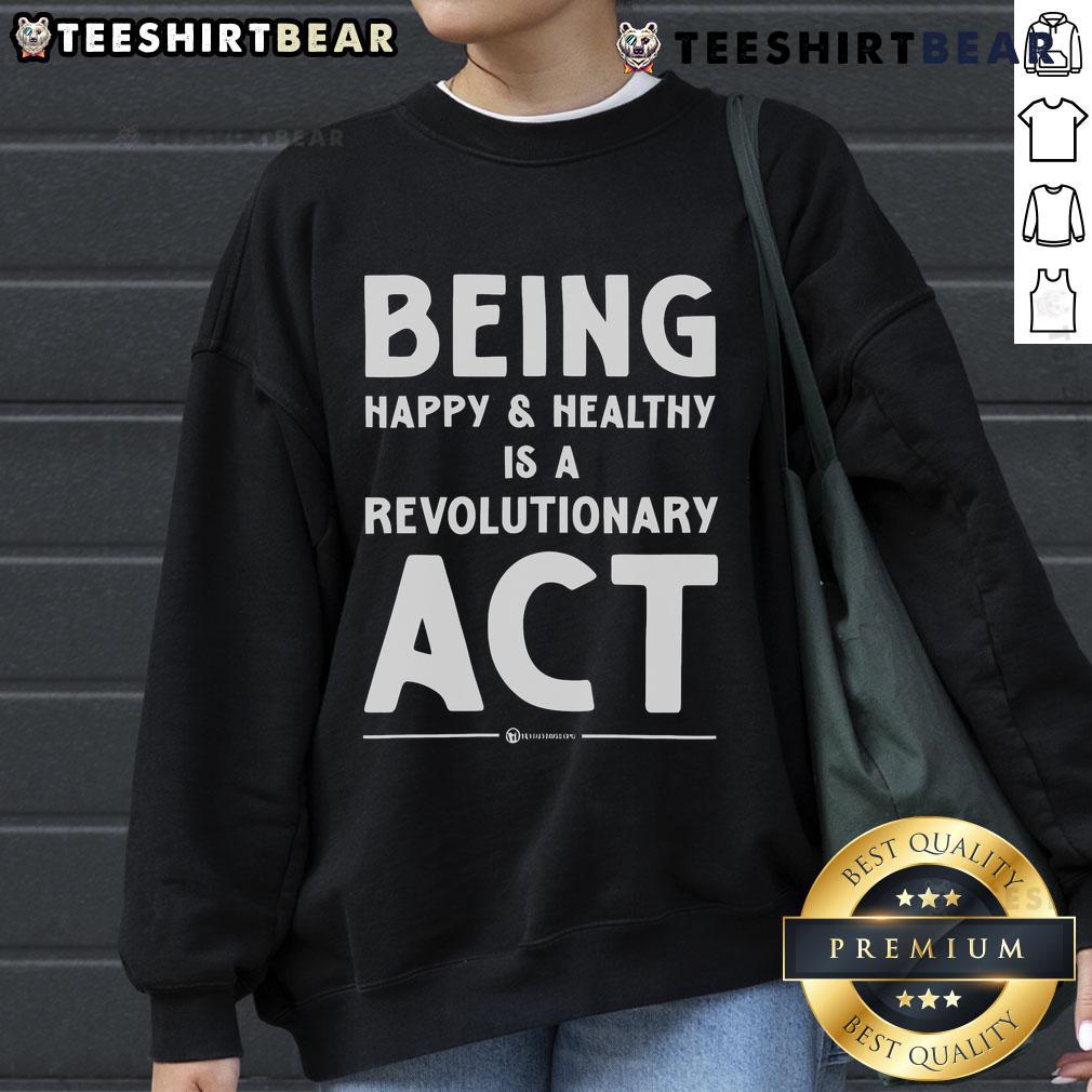 Top Being Happy and Healthy is a Revolutionary Act sweatshirt displayed on a hanger, promoting wellness and positivity.