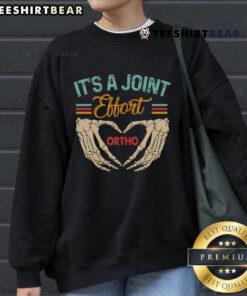 Good orthopedic surgeon and ortho nurse wearing 'It's a Joint Effort' sweatshirt, showcasing teamwork in orthopedic care.