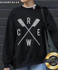 Top rowing crew wearing sweatshirts, showcasing crossed oars, teamwork, and dedication in a competitive rowing environment.