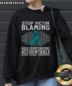 Teal ribbon sweatshirt promoting sexual assault awareness, featuring the slogan 'Top Stop Victim Blaming' for support.