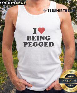 Model wearing 'Top I Love Being Pegged' tank top, showcasing bold text design in a trendy, casual setting.
