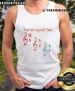 Musician wearing a stylish tank top with 'Top These Are Difficult Times' graphic, showcasing artistic expression and fashion.