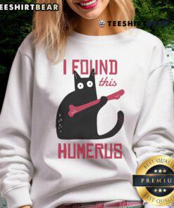 Funny cat wearing a I found this humerus sweatshirt, holding a bone, showcasing its playful personality.