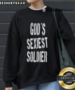 Lizzo wearing 'God's Sexiest Soldier' sweatshirt, showcasing bold style and confidence in a vibrant setting.