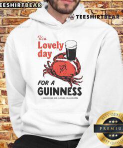 Person wearing a 'Top Crab It's A Lovely Day For A Guinness' hoodie, enjoying a sunny day at the beach.