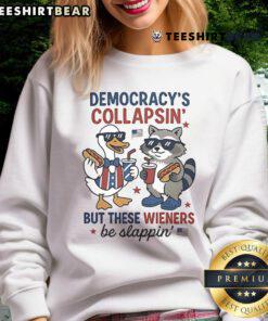 Alt Text: Top Duck and Raccoon Democrat Fourth of July shirt featuring 'Democracy's Collapsing, But These Wieners Be Slapping' design.