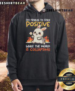 Cute bunny wearing a hoodie with the phrase I'm trying to stay positive while the world is collapsing, perfect for cozy vibes.
