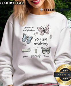 Alt Text: Cute sweatshirt with 'You Are Not Broken, You Are Evolving, Give Yourself Time' slogan, perfect for cozy casual wear.