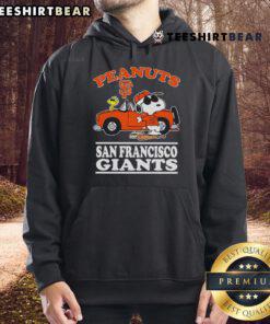 Good San Francisco Giants fans posing with peanuts next to a car wearing a hoodie at a baseball game.
