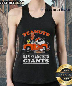 Good San Francisco Giants fan wearing a peanuts tank top poses next to a car, showcasing team spirit and style.