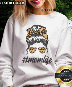 Stylish mom in a leopard pattern sweatshirt and shades, rocking a cool messy bun, embodying top classy mom life.