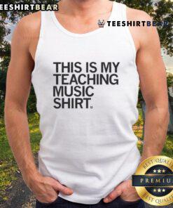 Alt Text: Happy music teacher wearing 'This Is My Teaching Music' tank top, showcasing passion for music education in a vibrant classroom.