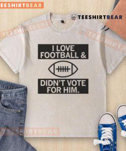 Top I Love Football And Didn't Vote For Him washed t-shirt displayed on a hanger, showcasing a casual and playful design.
