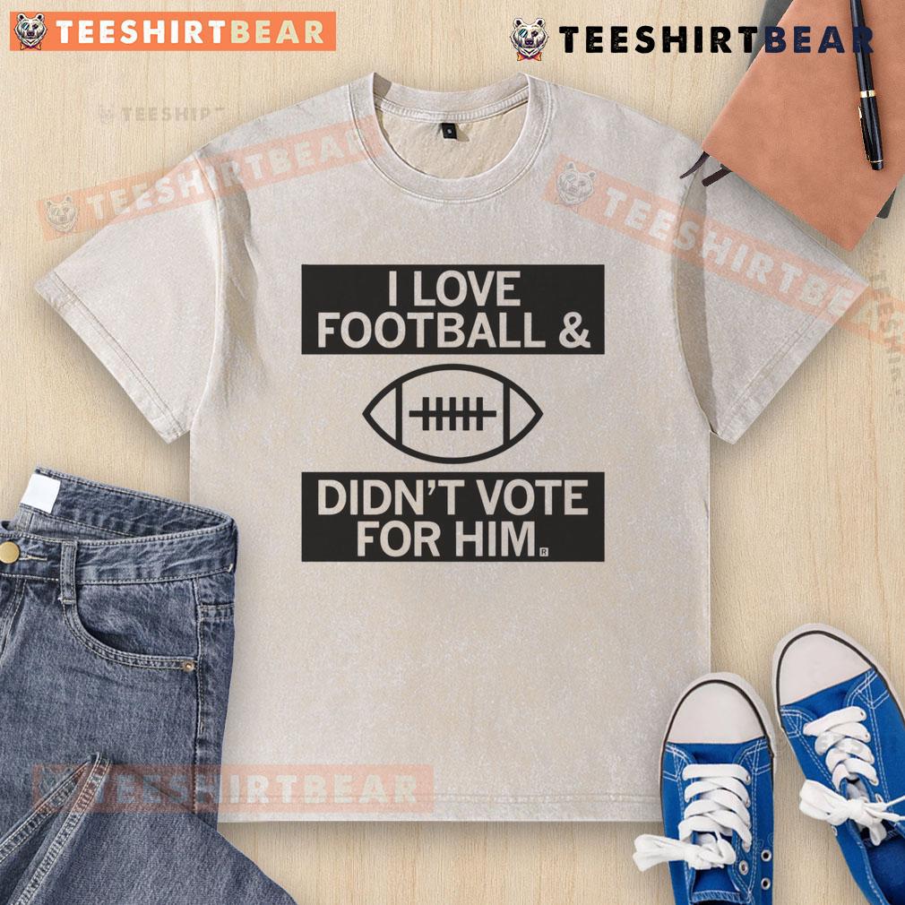 Top I Love Football And Didn't Vote For Him washed t-shirt displayed on a hanger, showcasing a casual and playful design.