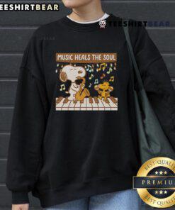 Cozy Snoopy and Woodstock sweatshirt featuring 'Music Heals The Soul' design, perfect for fans of Peanuts and music lovers.