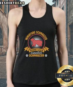 Adorable Miniature Schnauzer wearing a stylish tank top, showcasing its playful personality and fluffy fur.