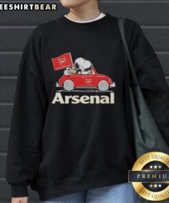 Snoopy and Woodstock driving an Arsenal red car on a sweatshirt, raising a flag in a playful design.