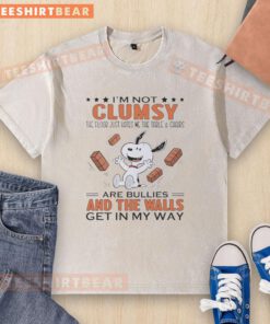 Alt Text: Funny Snoopy t-shirt featuring 'I'm not clumsy, the floor just hates me' with a table and chairs design.
