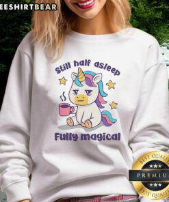 Alt Text: Top unicorn holding a coffee mug, looking sleepy in a magical sweatshirt, perfect for cozy mornings.