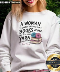 Alt Text: Woman wearing 'A Woman Cannot Survive On Books Alone She Also Needs Yarn' sweatshirt, showcasing a cozy reading and crafting vibe.