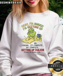 Cozy Top Grinch sweatshirt featuring 'Okay, I'm awake, I'm getting up' design, perfect for holiday cheer and comfort.