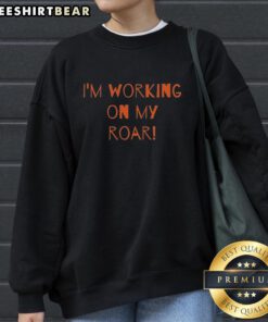 Cozy 'I'm Working On My Roar' sweatshirt displayed on a hanger, perfect for casual wear and motivational style.