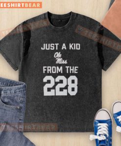 Top Just A Kid Ole Miss From The 228 washed t-shirt displayed on a rustic wooden background, showcasing its vibrant design.
