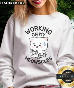 Person wearing a Meowscles sweatshirt while working at a desk, showcasing the popular gaming apparel.