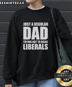 Premium 'Just A Regular Dad Trying Not To Raise Liberals' humor sweatshirt in casual style, perfect for dads with a sense of humor.