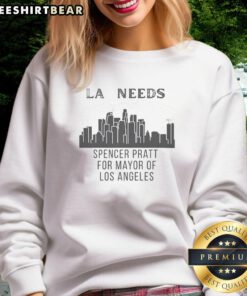 Spencer Pratt wearing a 'Los Angeles Needs Cityscape' sweatshirt against a vibrant LA cityscape background.